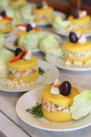 Representative photograph of Causa Limena. The photograph shows individual portions with olives and extra garnish; this draft sets causa in one dish.