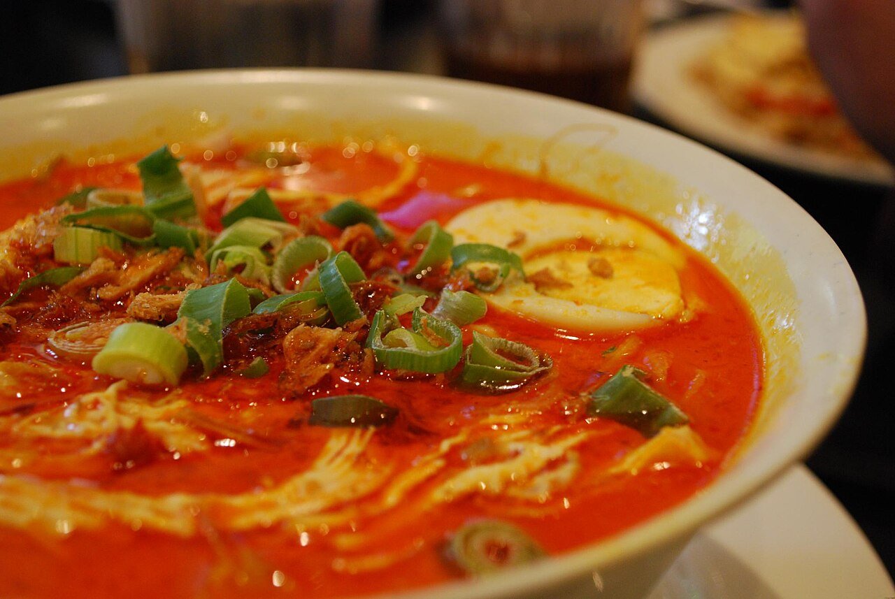 Representative photograph of Curry Laksa. The photograph shows chicken curry noodle soup with egg and other garnishes; this draft omits the egg topping.