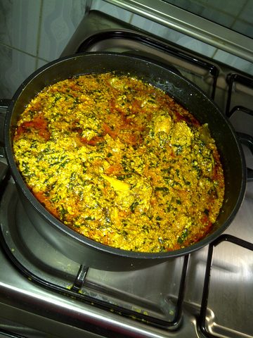 Representative photograph of Egusi Soup. The photograph shows egusi soup in a cooking pan; its meat and greens can differ from this beef-and-spinach draft.