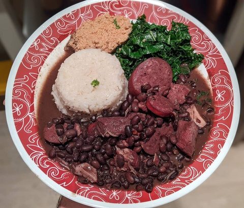 Representative photograph of Feijoada. Rice, greens and cassava flour are shown as accompaniments.