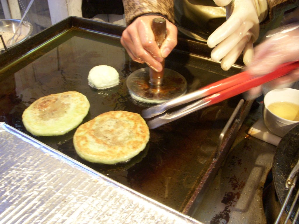 Representative photograph of Hotteok. The photograph shows hotteok cooking on a griddle, rather than a plated serving.