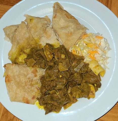 Representative photograph of Jamaican Curry Goat. The photograph includes roti and slaw not included in this draft.