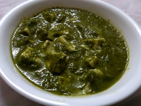 Paneer pieces in a dark green spinach gravy