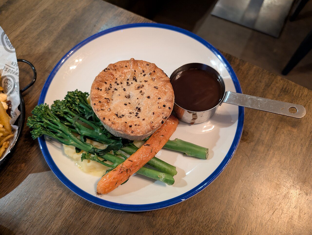 Representative photograph of Steak and Ale Pie. The photograph shows an individual pie with side vegetables; this draft makes one large pie.